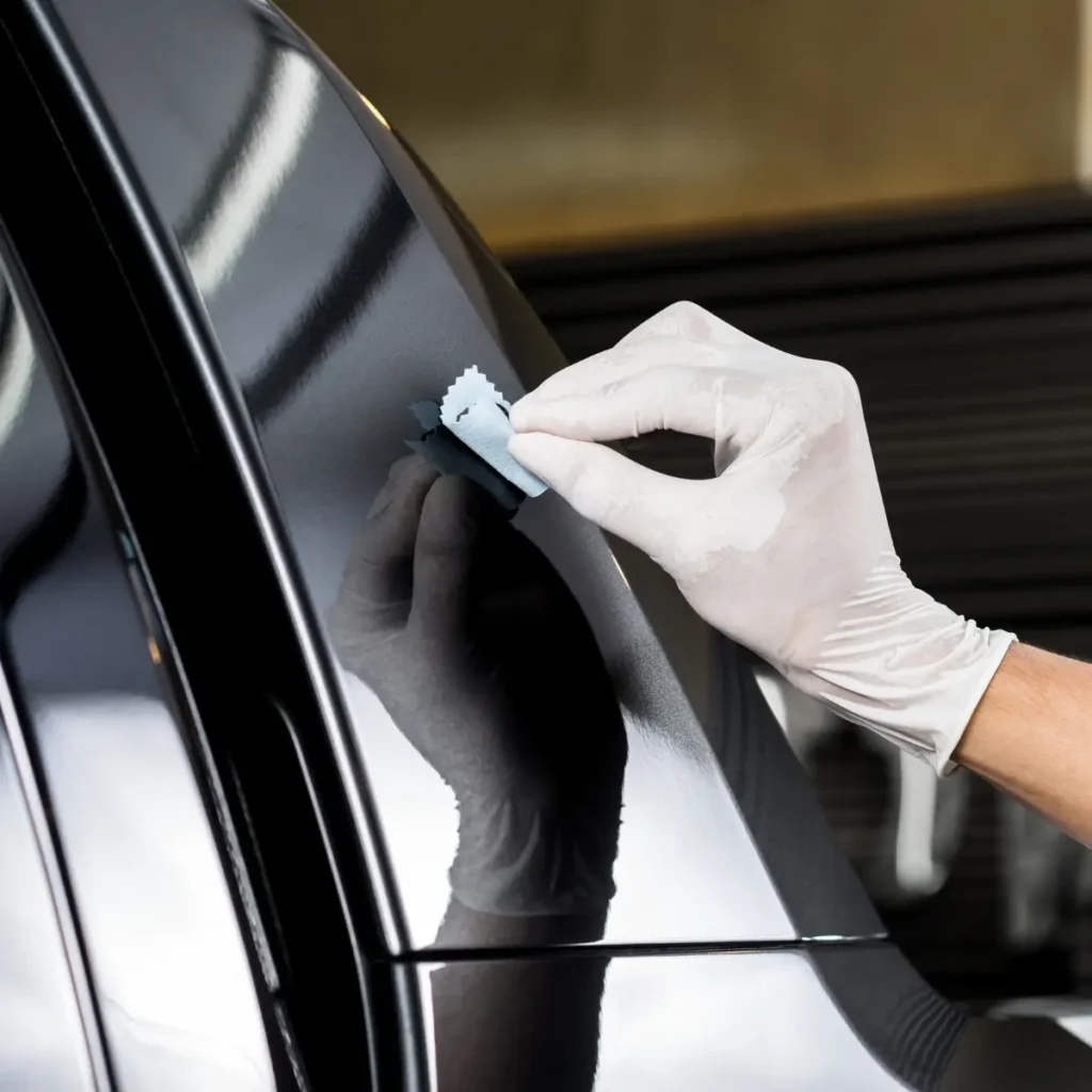 mão tirando um adesivo da lataria do carro