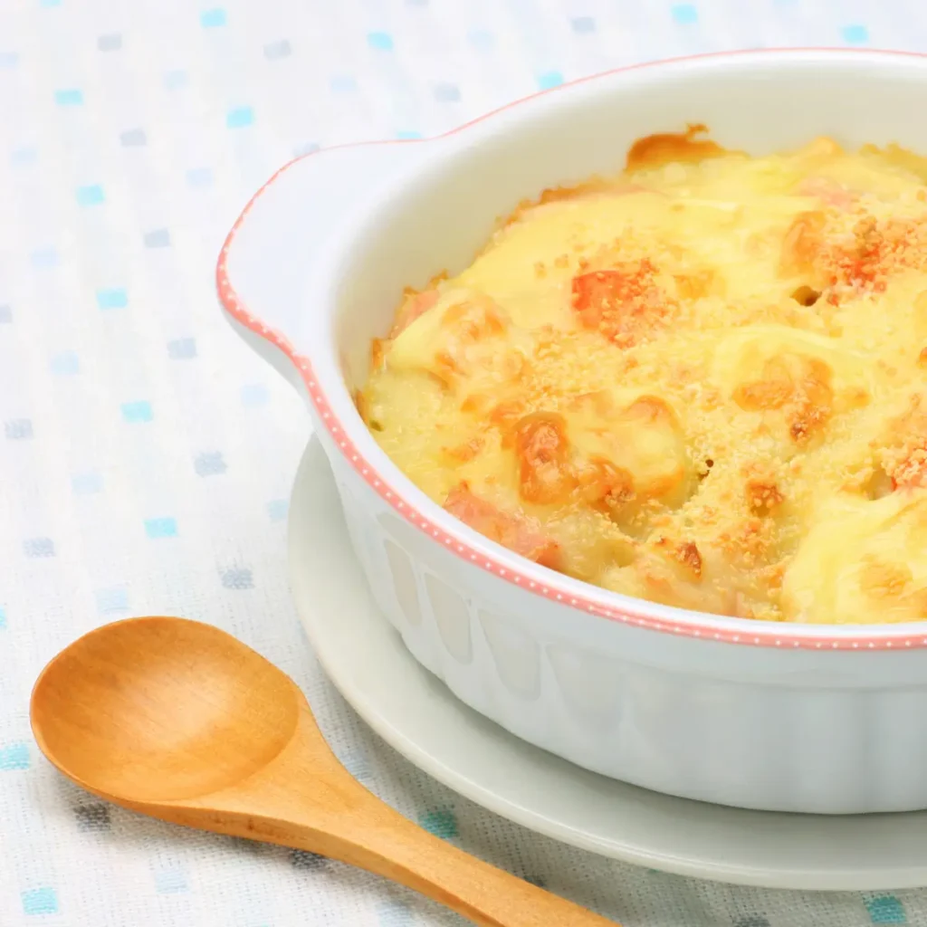 travessa branca com gratinado e uma colher de pau ao lado.