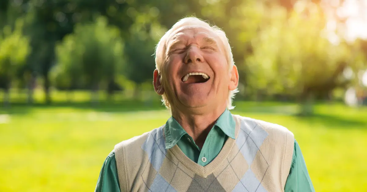 Senhor sorrindo ao ar livre com um gramado verde ao fundo